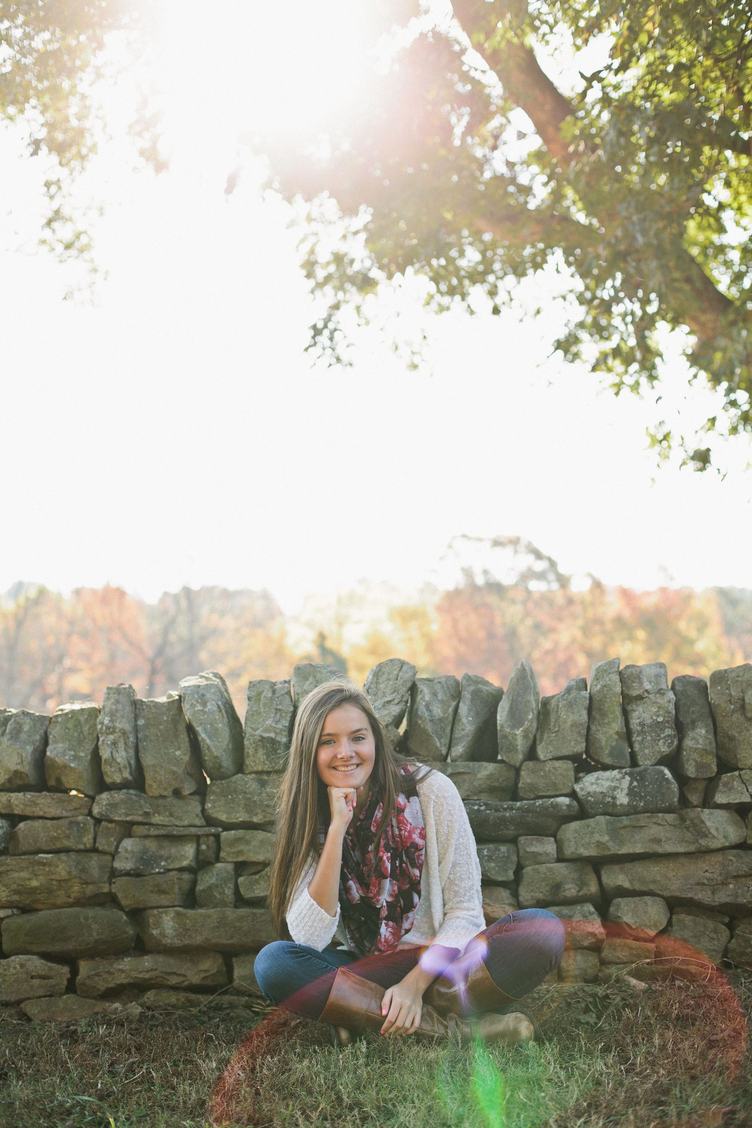 Autumn afternoon portrait session by stone wall with sun flare and fall foliage.