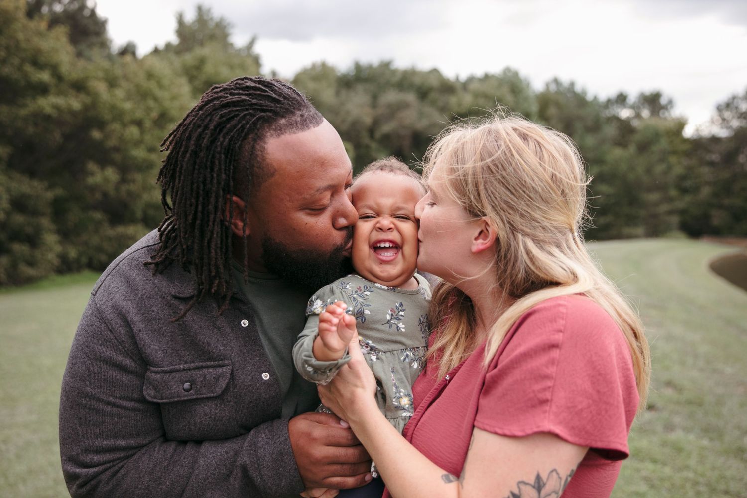 A candid moment capturing joyful laughter and embraces during a family photo session outdoors.