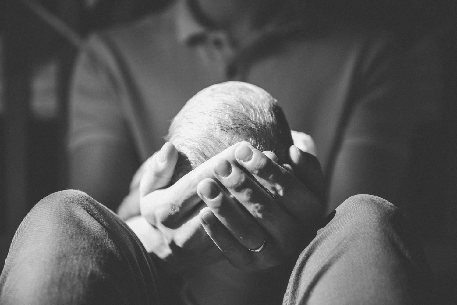 Black and white intimate portrait of family bonding with newborn baby.