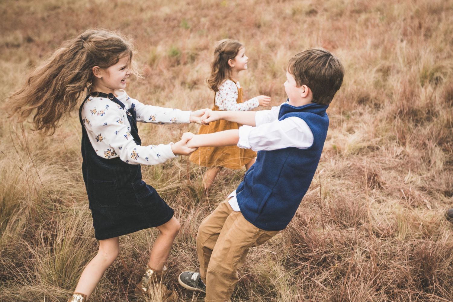 Children playing and spinning in a circle in a golden field.