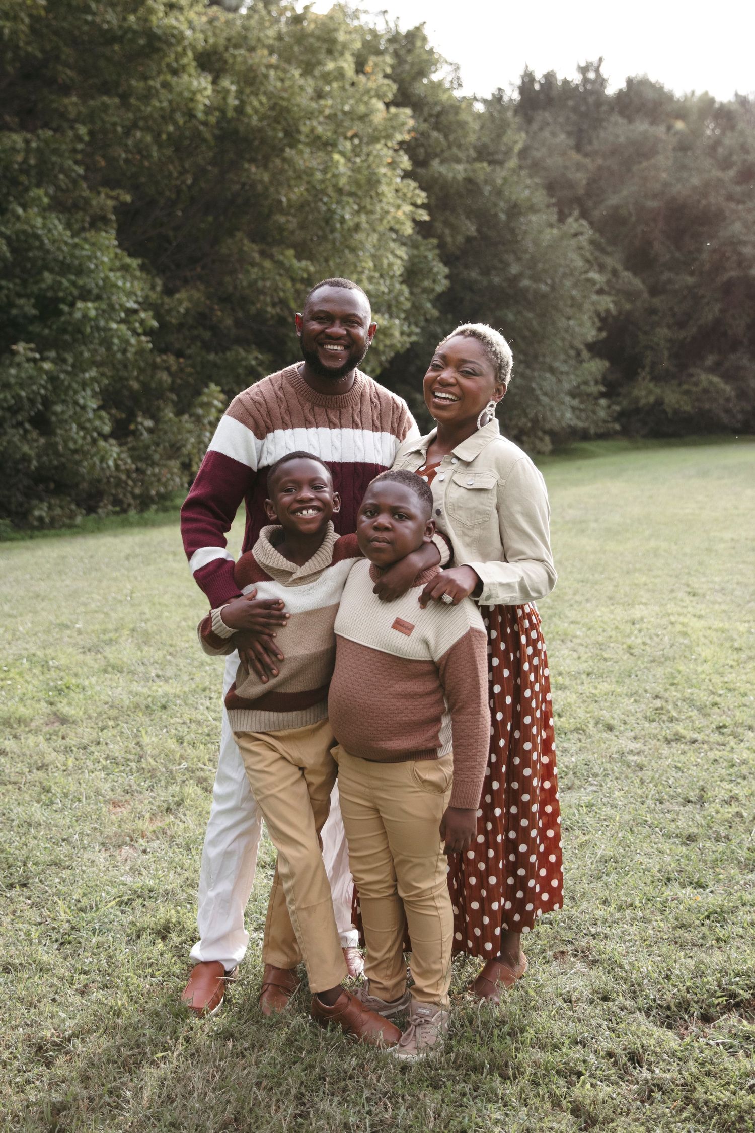 Family of four shares laughter and embraces while posing in casual autumn attire.