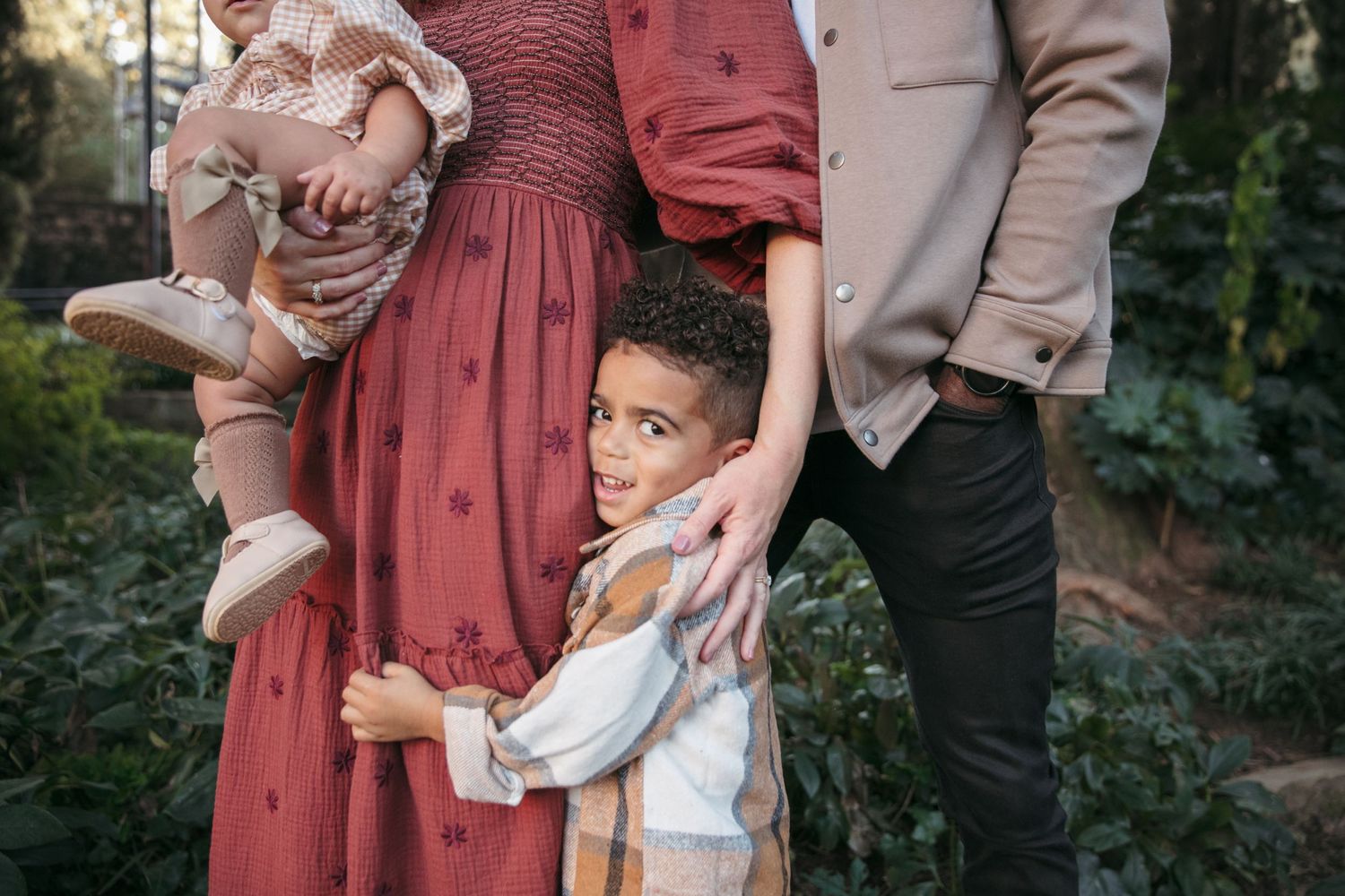 A sweet family moment captured in a garden setting with natural lighting.