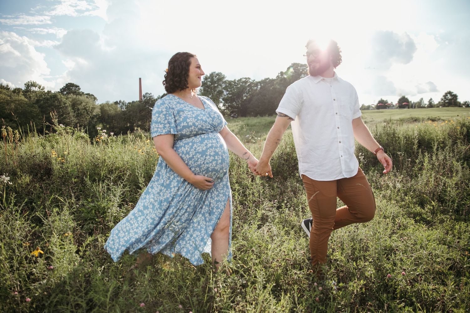 Couple walking through sunny wildflower field on summer afternoon.