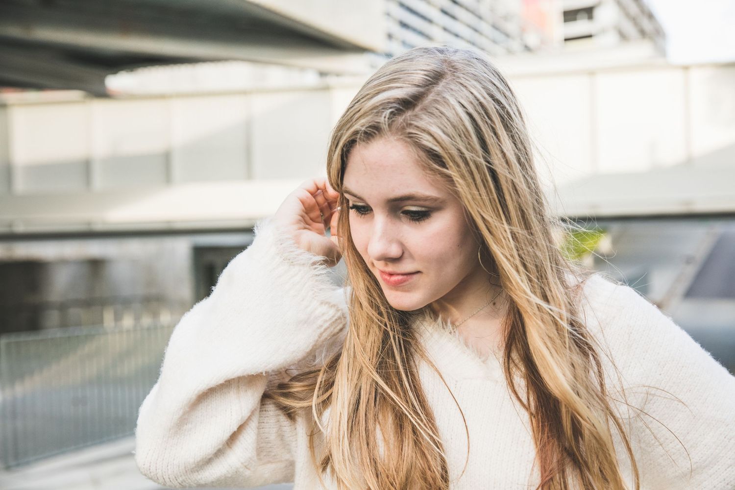 Soft natural lighting illuminates a casual urban fashion portrait with cream colored sweater.