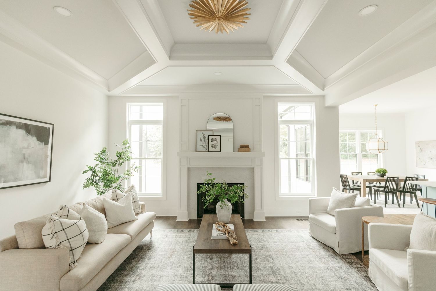 Bright modern living room with vaulted ceiling, white sofas, and a central fireplace in a coastal-inspired design.