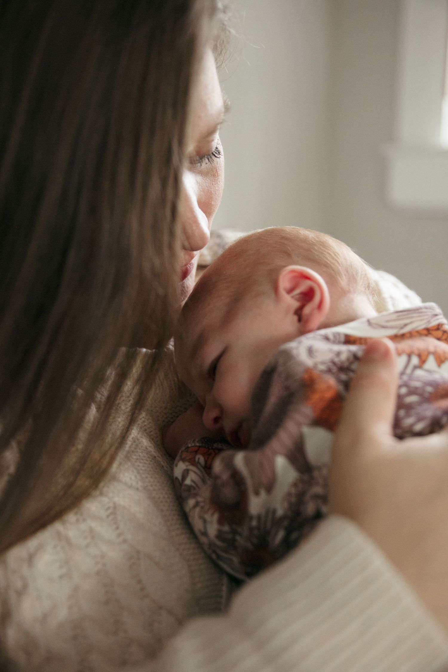 Close-up of gentle nurturing moment with sleeping infant in floral outfit.