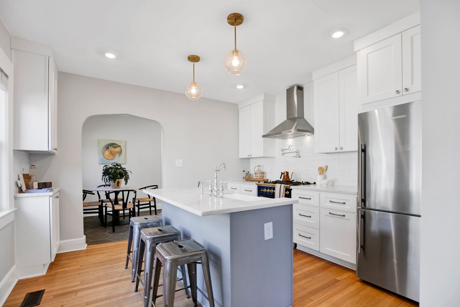 Modern kitchen renovation features sleek white cabinets, pendant lighting, and stainless steel appliances.