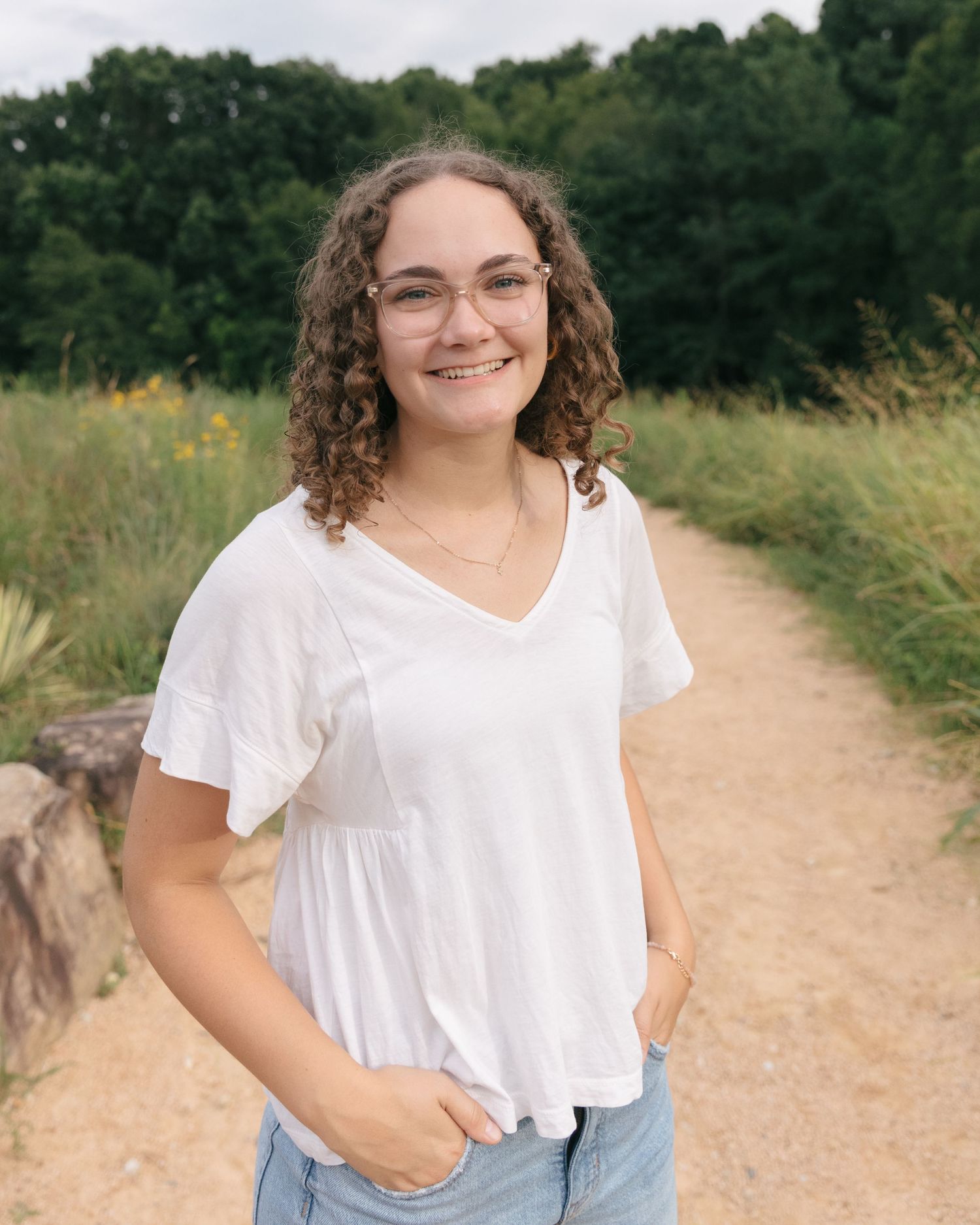 A series of casual outdoor portrait shots in a bright white top against a dirt path and green foliage background.
