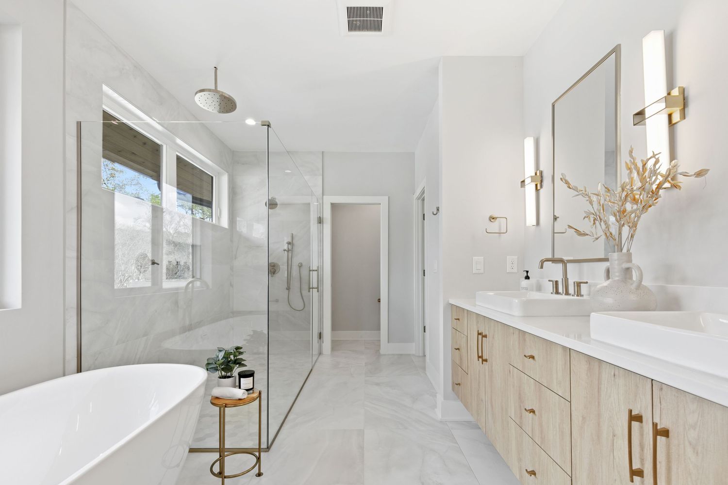 Bright bathroom featuring glass shower enclosure, twin vanities and modern fixtures.