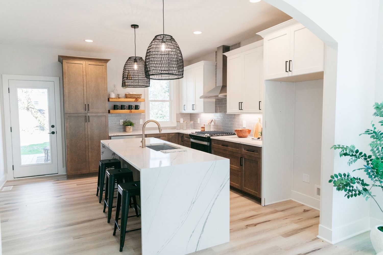 Open concept kitchen and dining space with modern pendant lighting and light wood flooring.