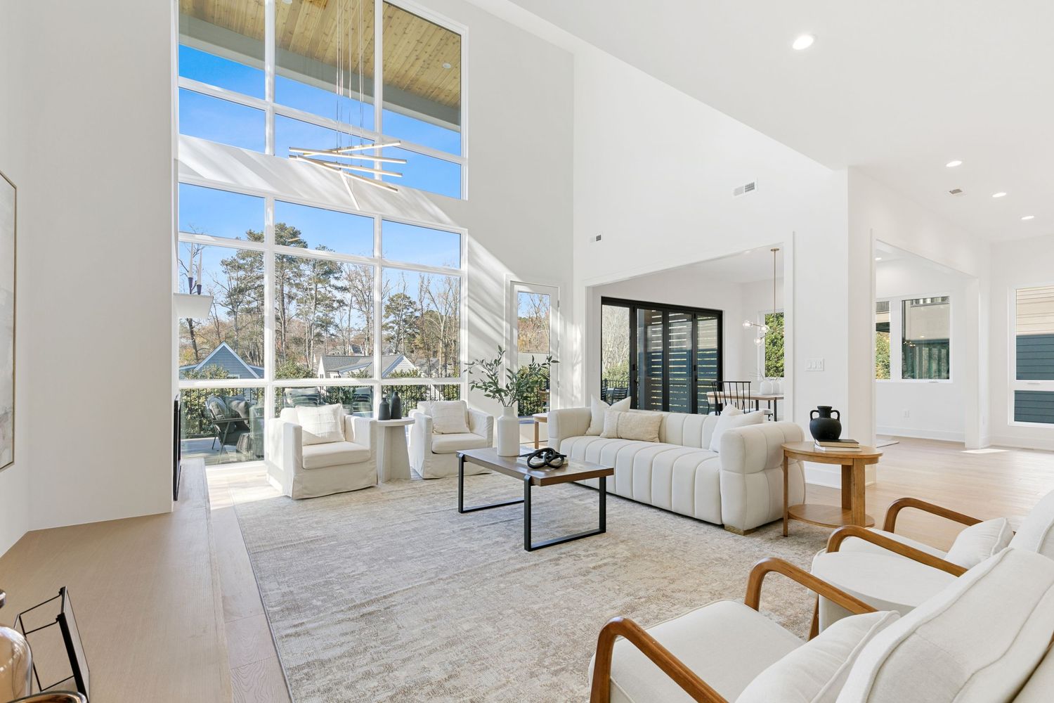 Expansive living area with wall-to-wall windows, white interior, and modern furniture creating an airy atmosphere.