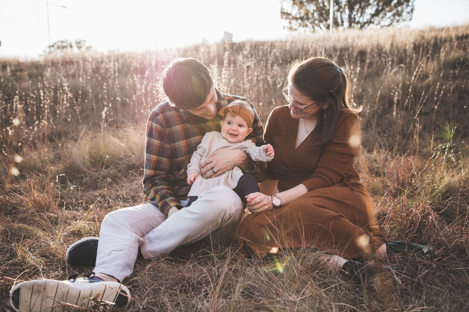 Family sitting together in a sun-lit field during golden hour.