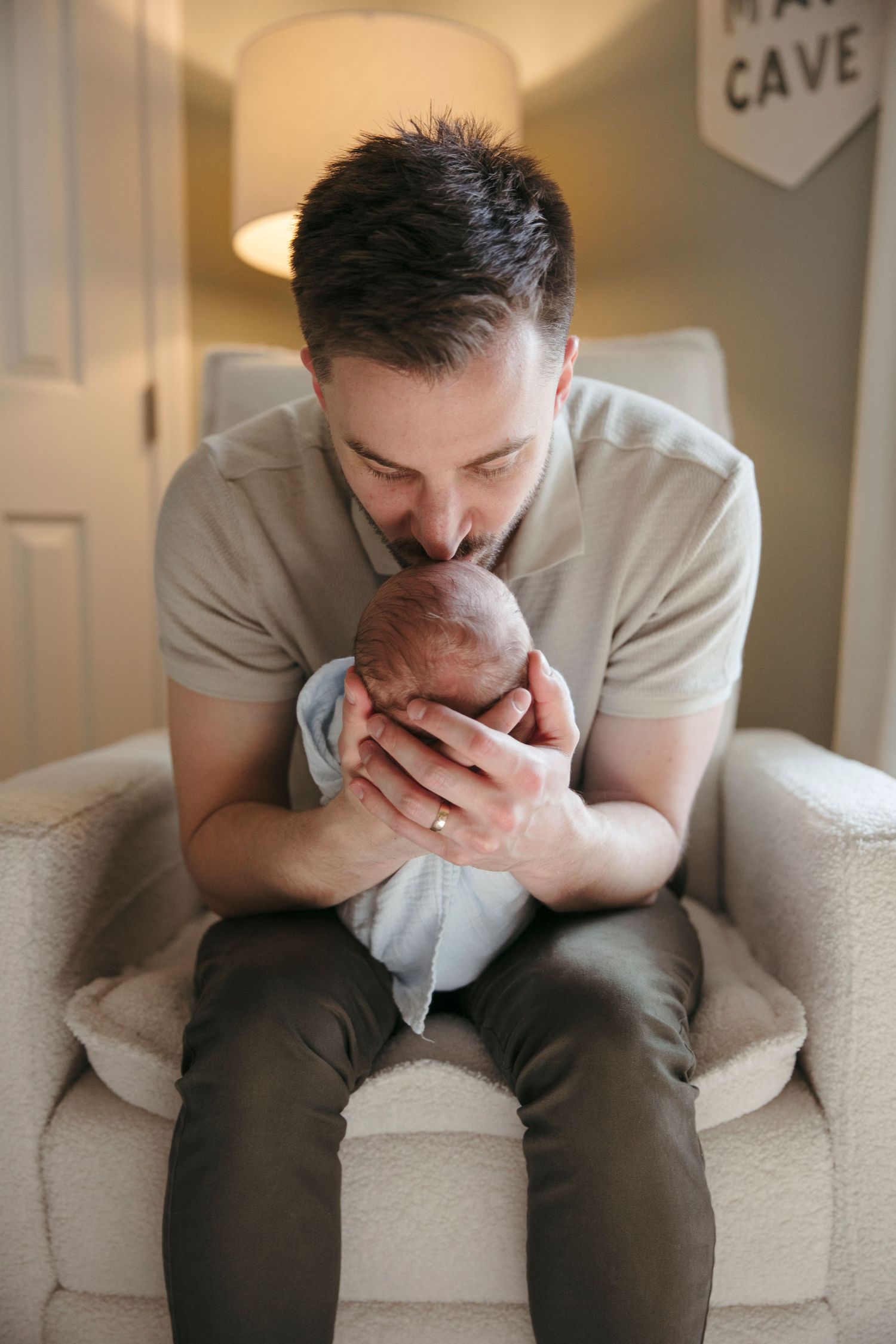 Emotional moment captured on white couch in modern nursery setting.