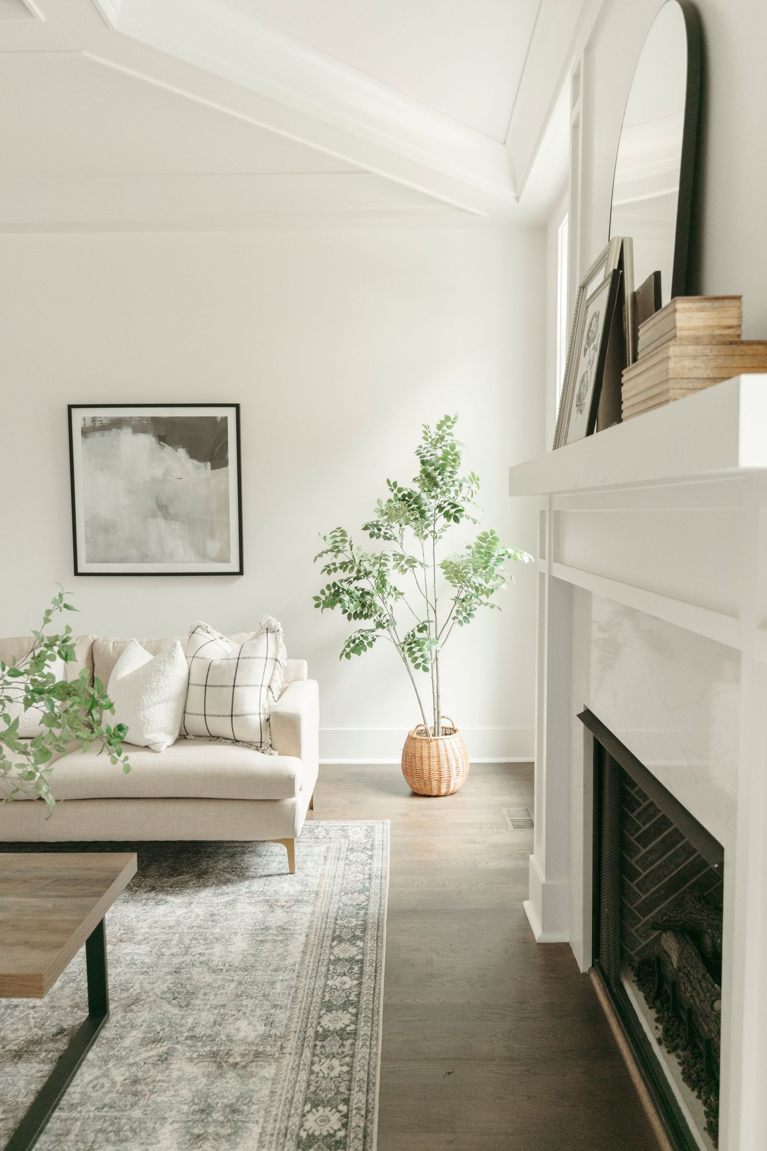 Modern living room with white walls, grey area rug, and built-in fireplace with minimalist decor.