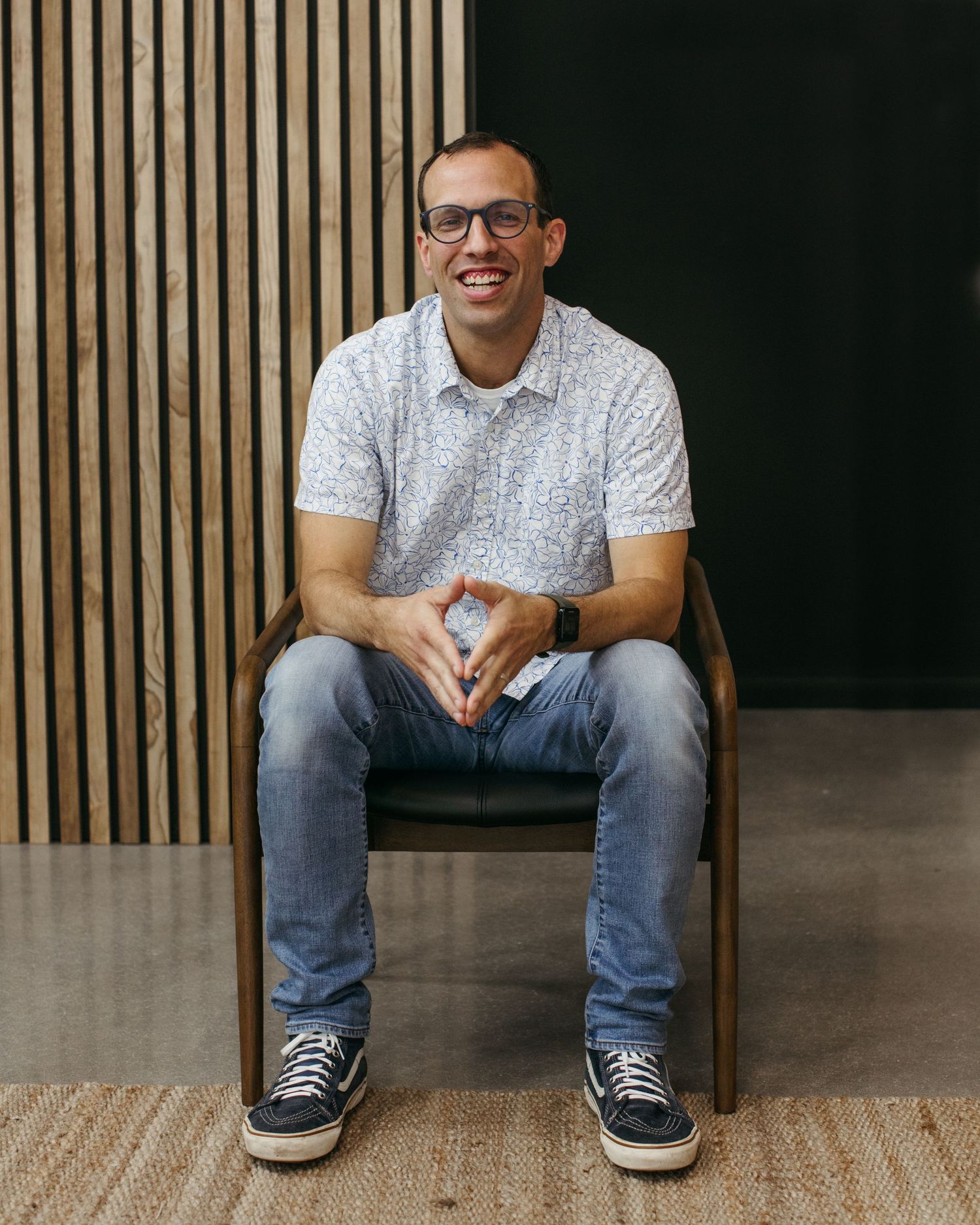 Casual lifestyle portraits showing person seated on chair against dark background with wood accents.