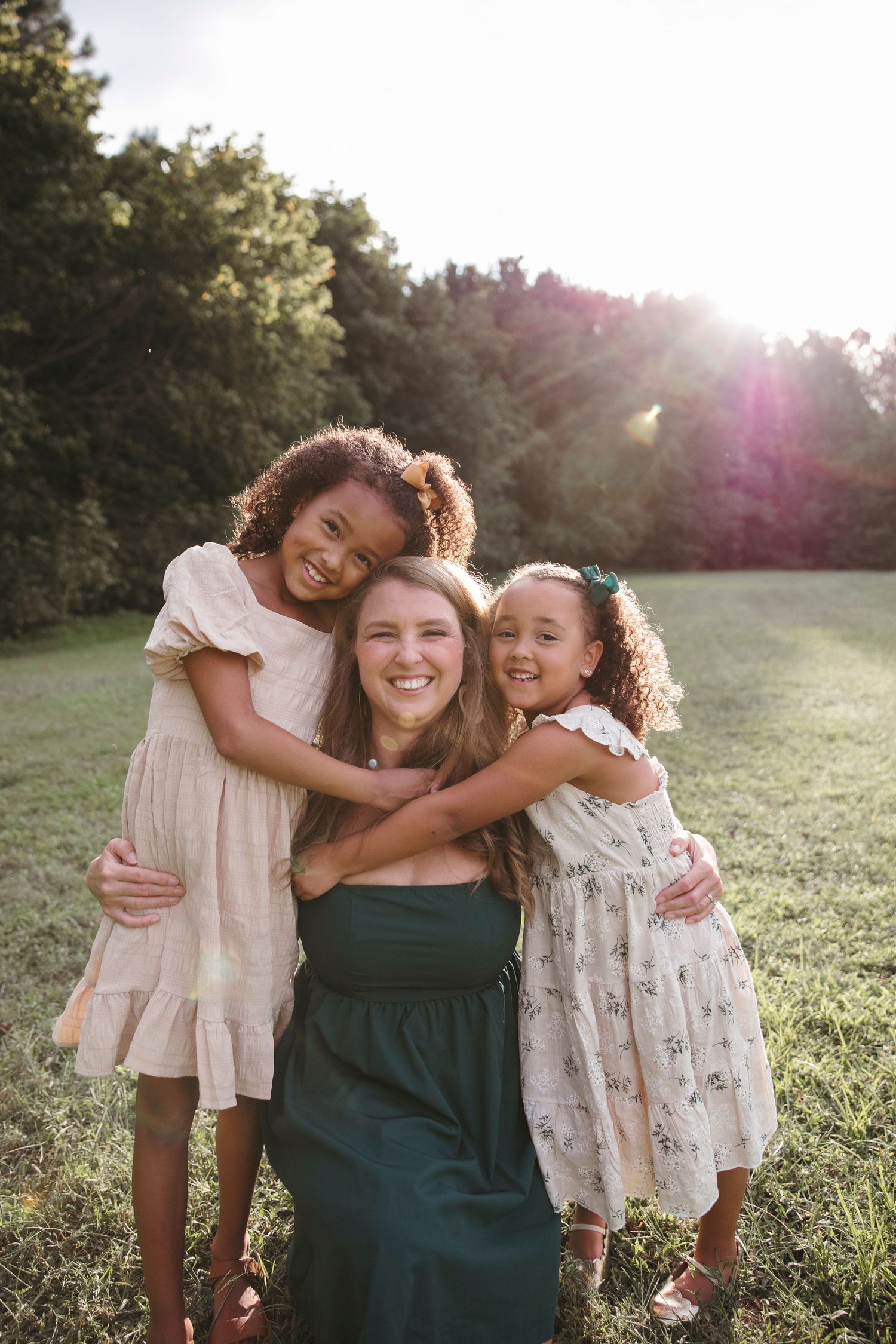 A heartwarming outdoor family portrait showing embraces and genuine smiles in natural lighting.
