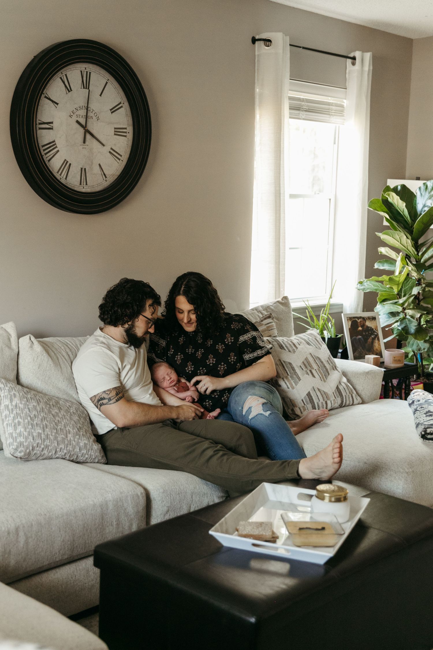 Cozy living room scene with family lounging on gray sectional sofa under wall clock.