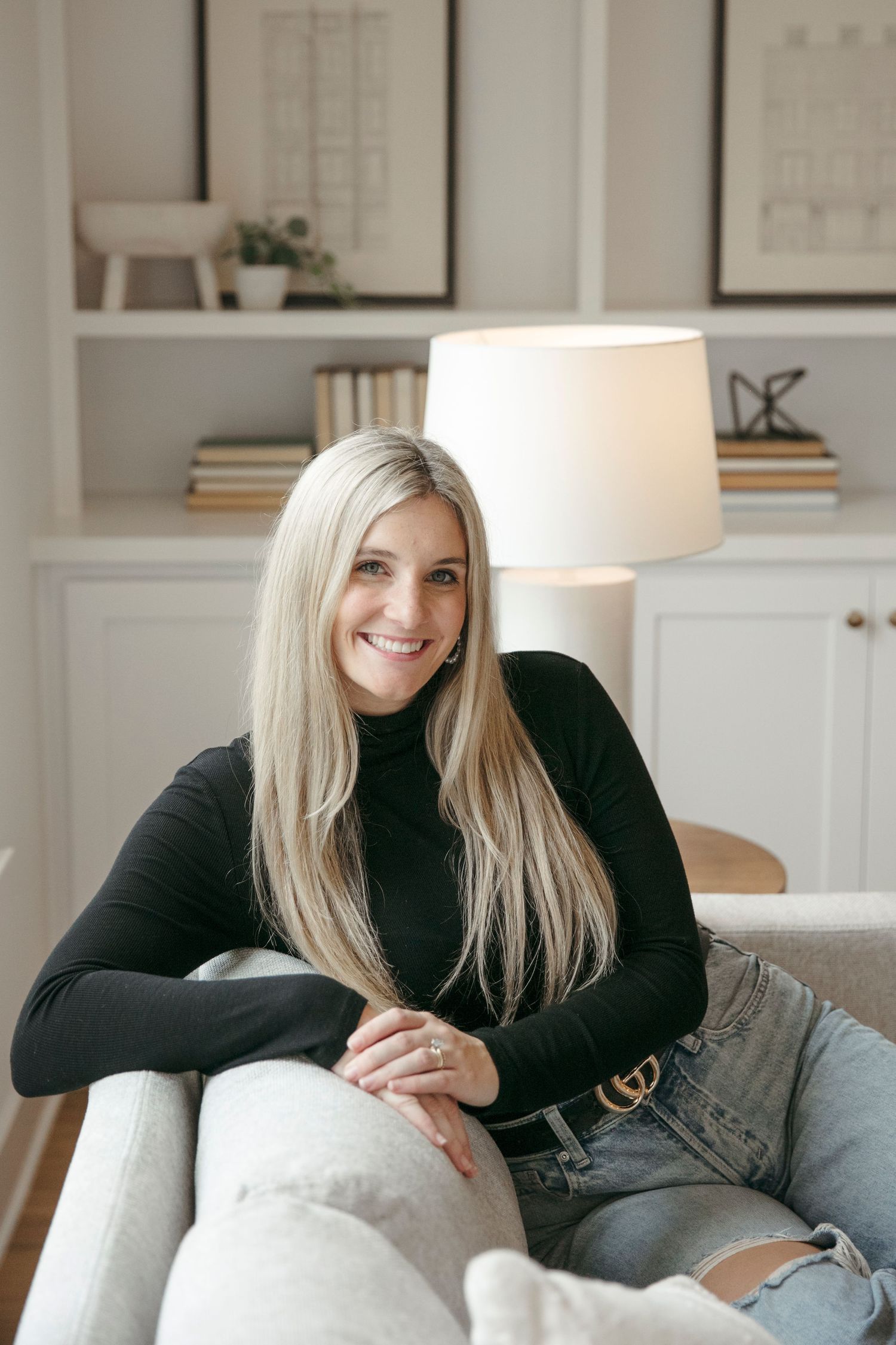 Interior lifestyle photo showcasing casual fashion with black turtleneck and ripped jeans.