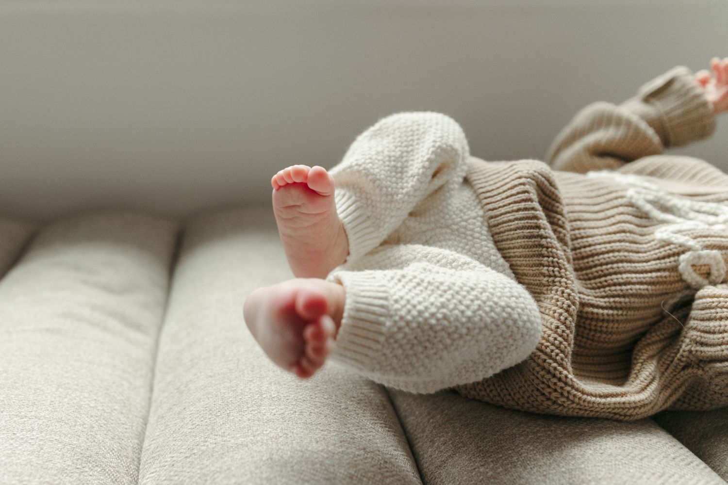 Close-up details of tiny newborn feet and knit blanket textures in soft lighting.
