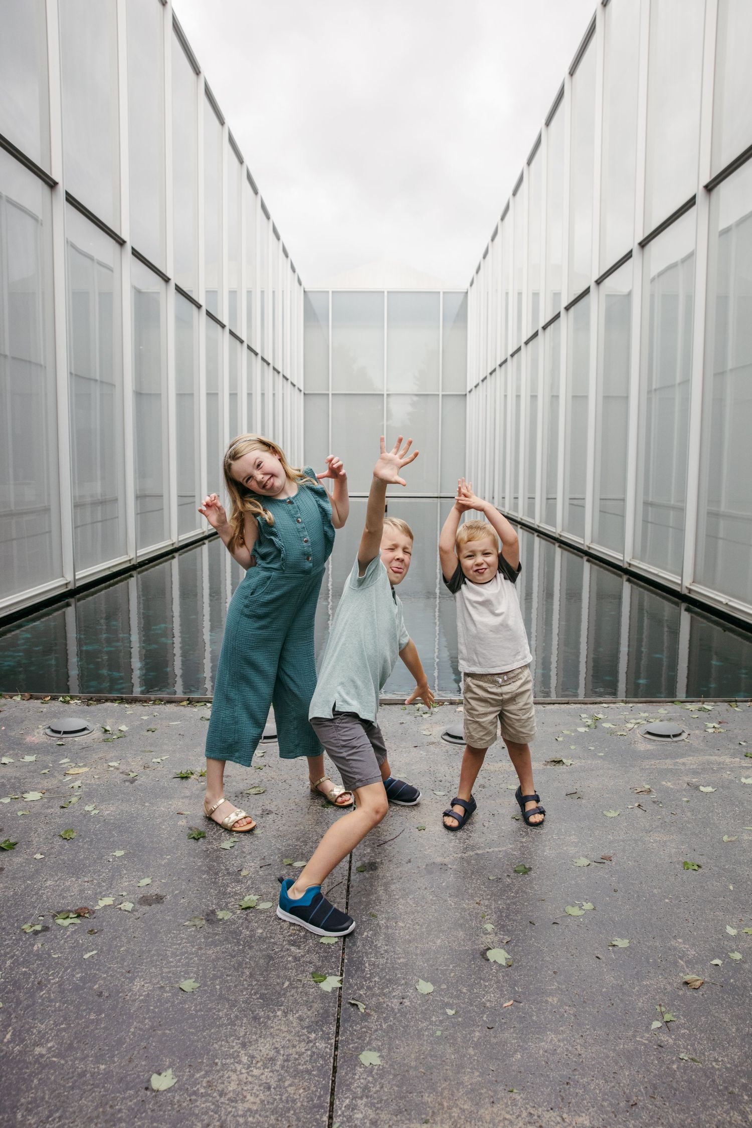 Children striking fun poses and dancing in industrial hallway setting.