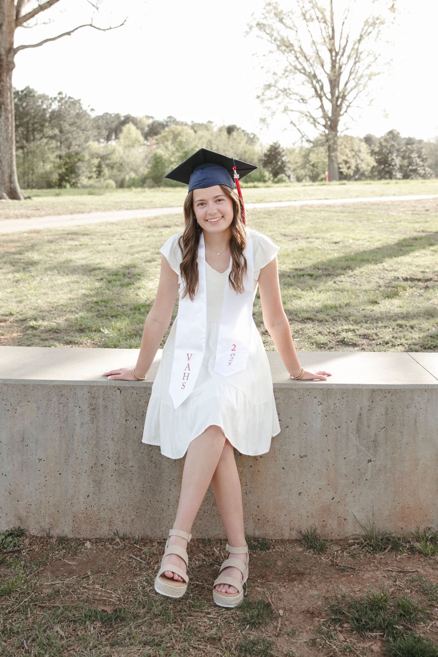 Collection of graduation photos featuring white dress and blue cap against natural outdoor backdrop.