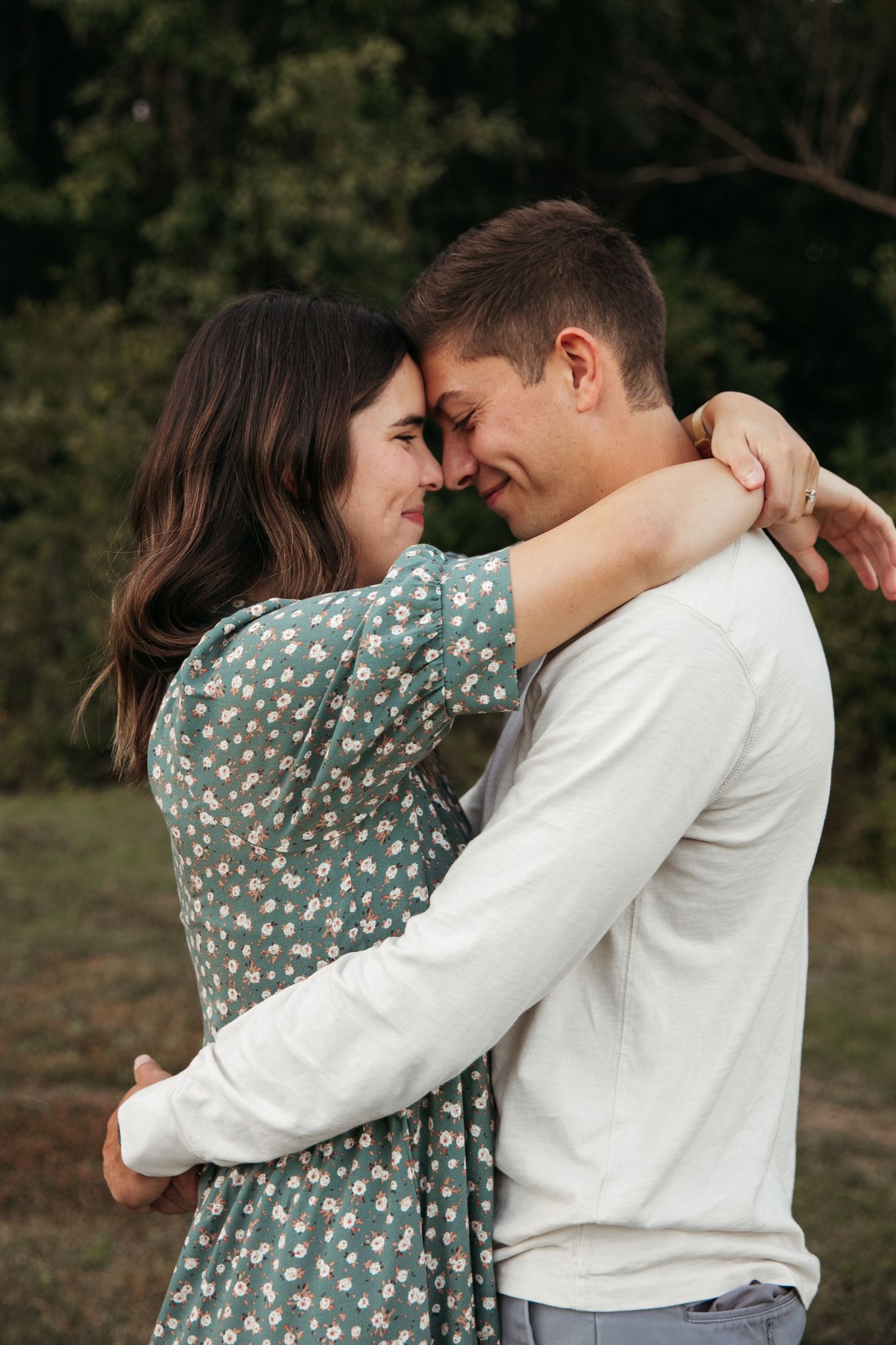Intimate moment between couple in casual attire embracing outdoors.