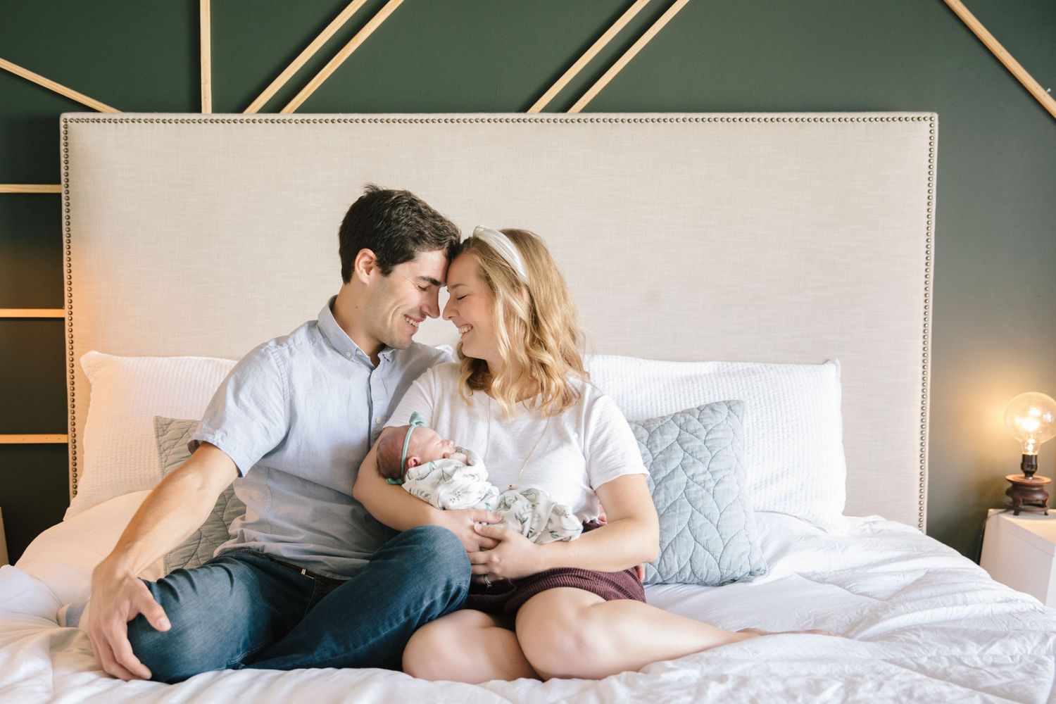 Parents lounging on white bed sharing intimate moments.