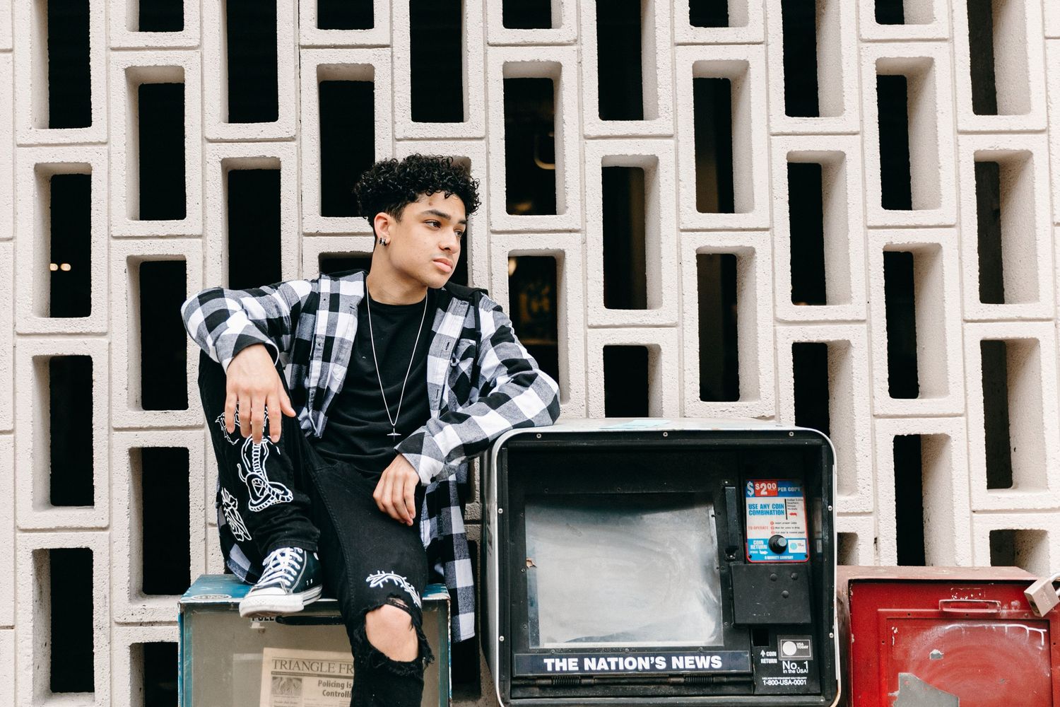 Urban fashion portrait with vintage TV prop against modernist architectural wall backdrop.