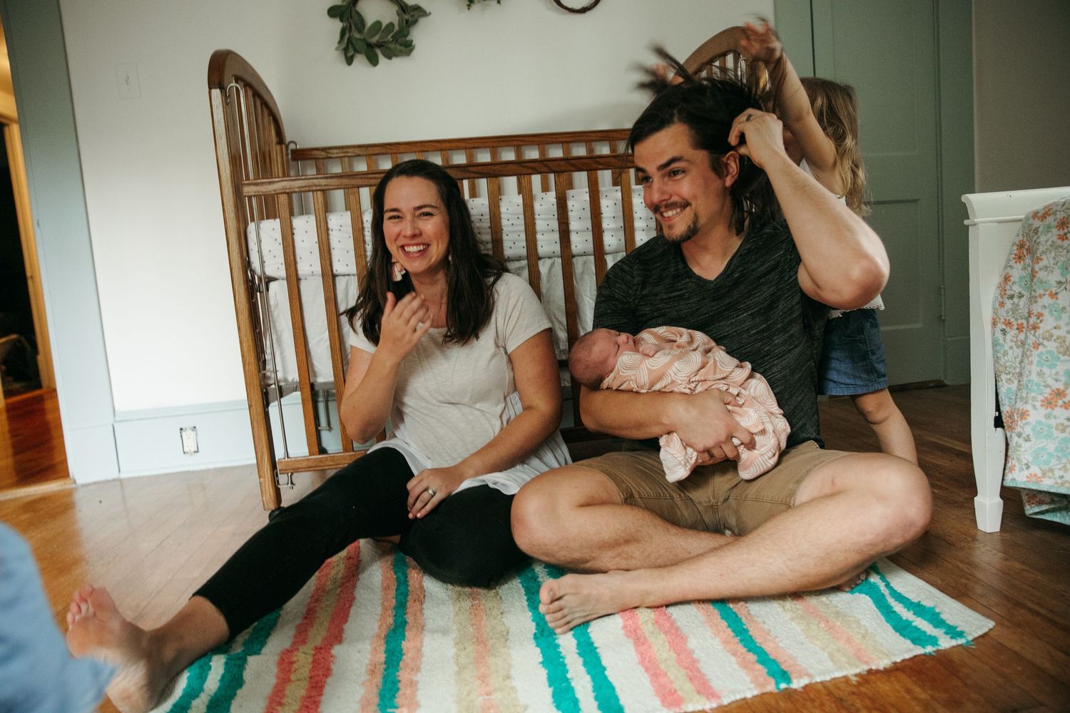 People relaxing and having fun together on a striped blanket at home.