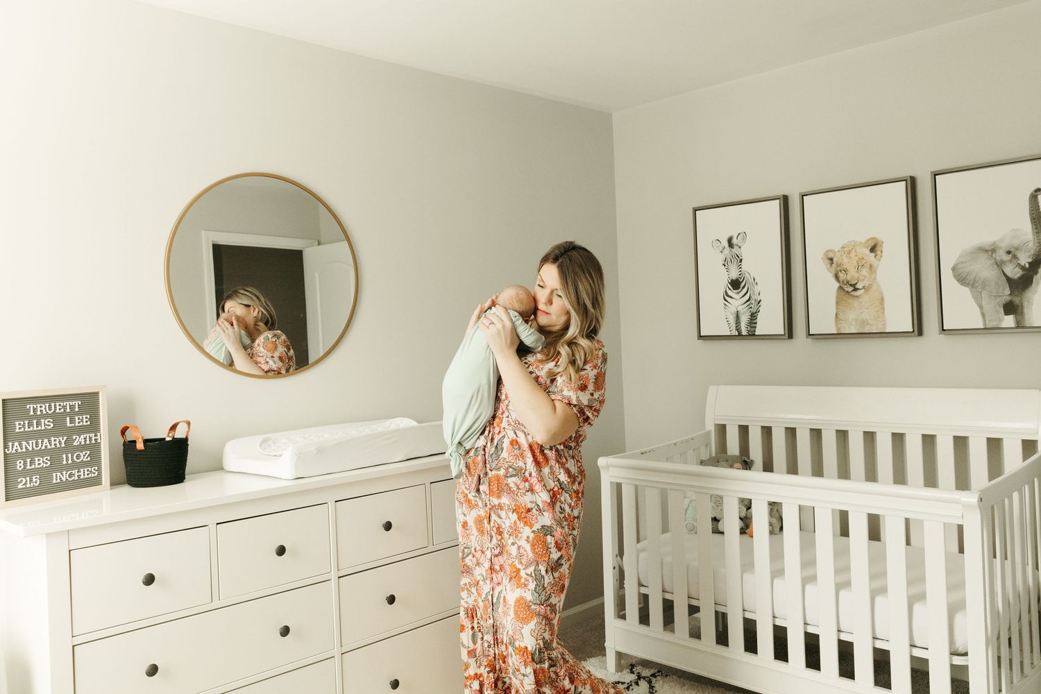 Nursery scene with white furniture and animal prints on wall.