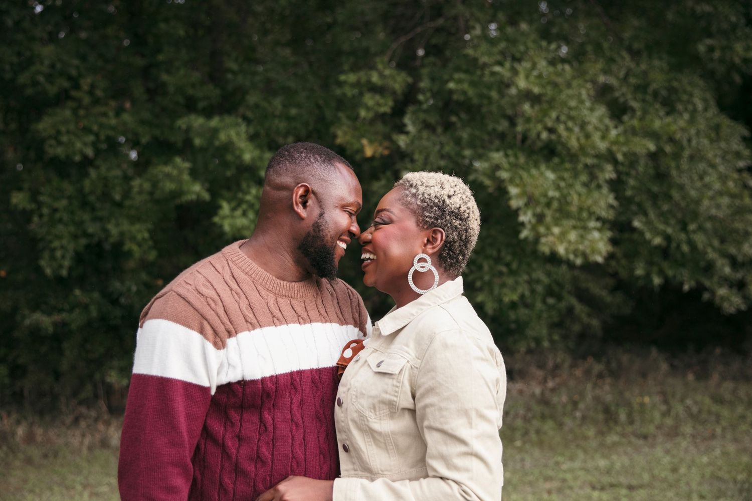 A romantic couple sharing an intimate moment outdoors while wearing casual sweaters in autumn.