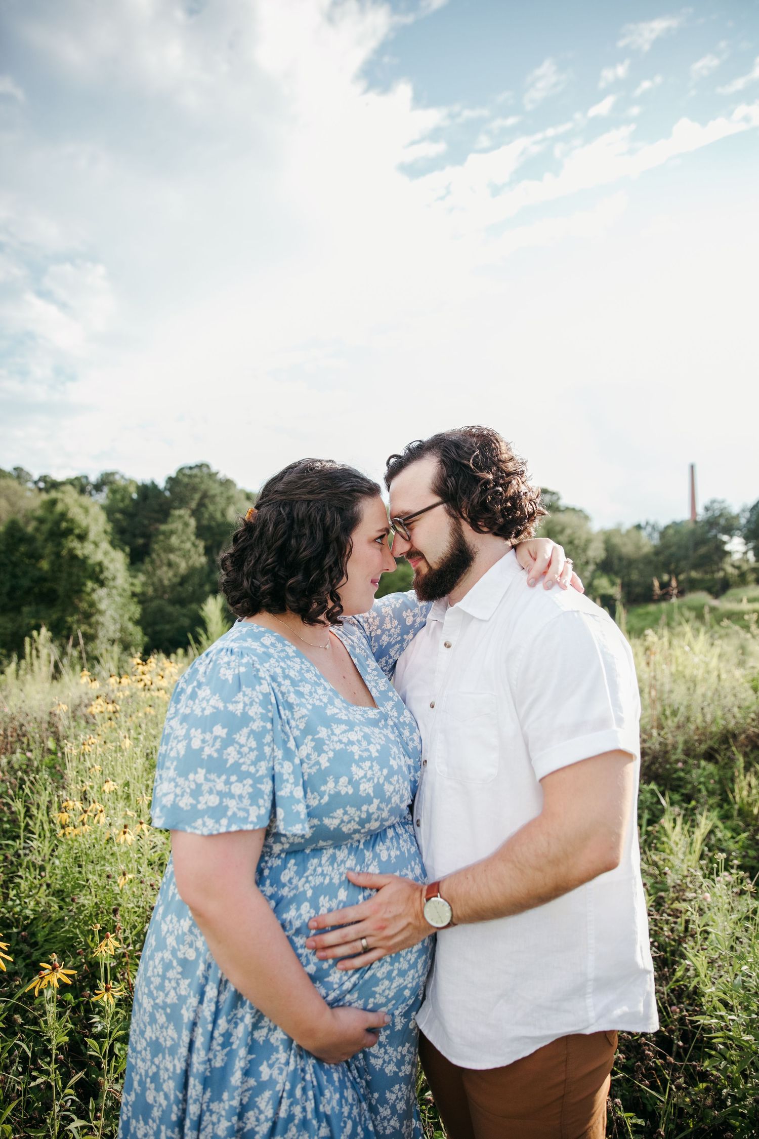 Intimate moment captured between couple in flowery field on sunny day.