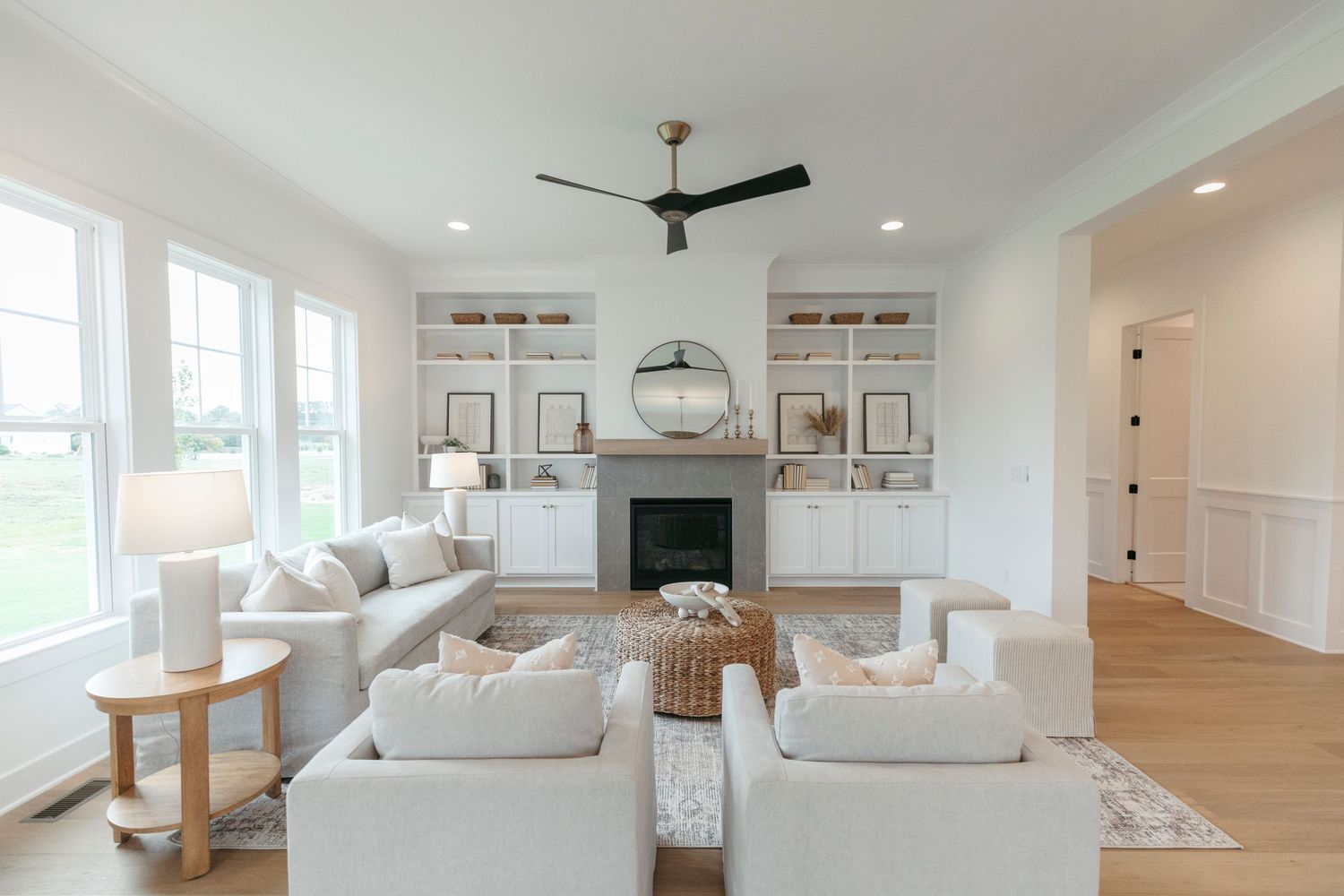 Coastal style living room with built-in shelving, fireplace and comfortable white seating.