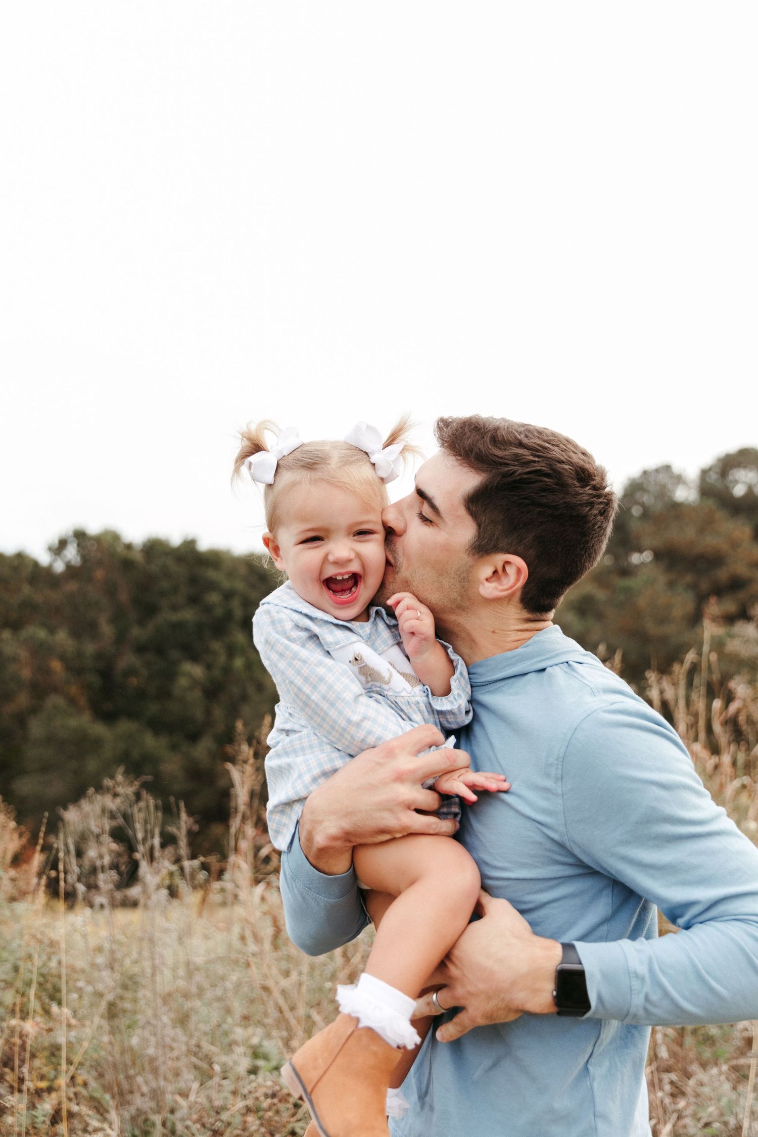A candid moment of laughter and affection captured in a field during golden hour.