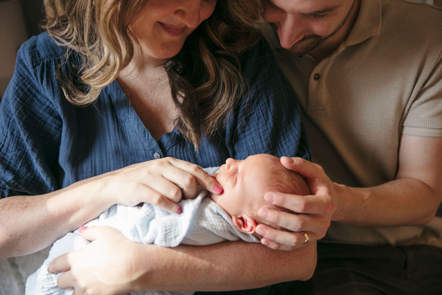Close-up of tender family moment with newborn baby in cozy home environment.