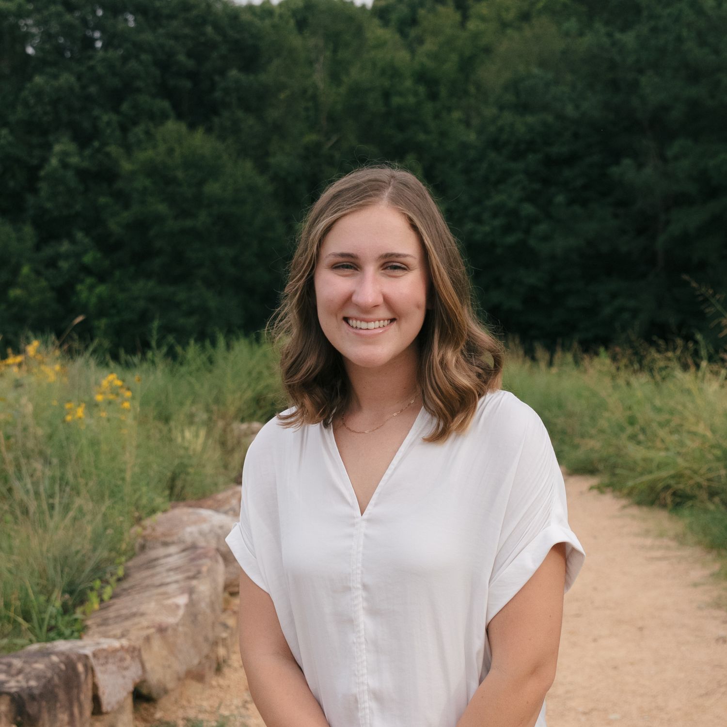 Casual outdoor portrait on dirt path with natural summer foliage.
