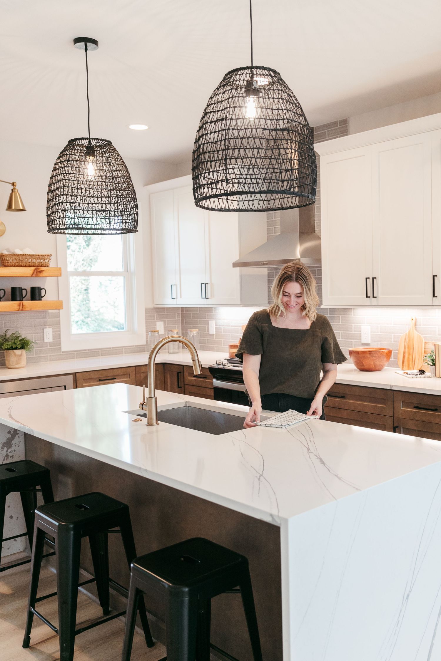 Modern white kitchen with black pendant lights and marble countertops showcases contemporary design.
