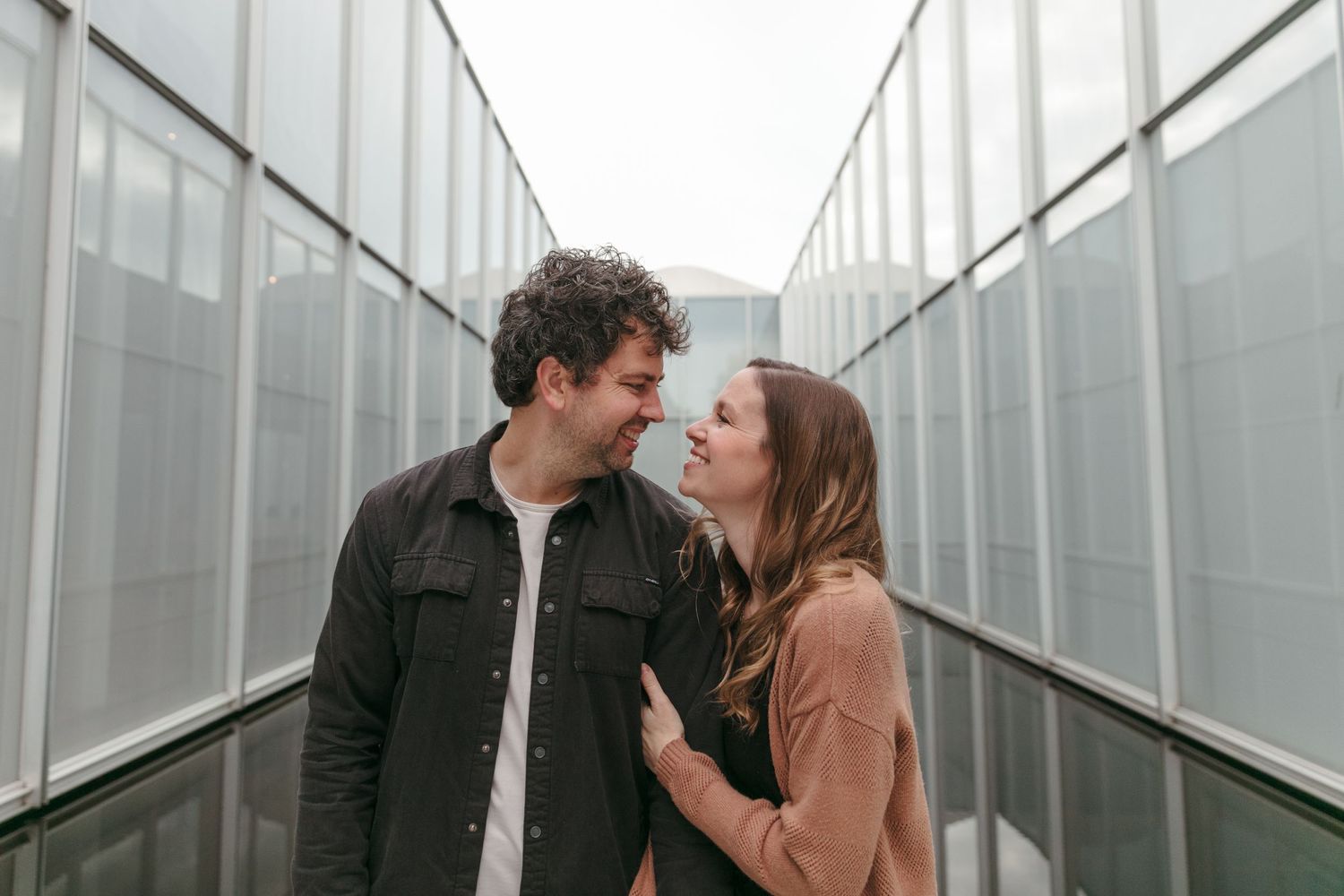 Couple sharing intimate moment in modern hallway with white walls.