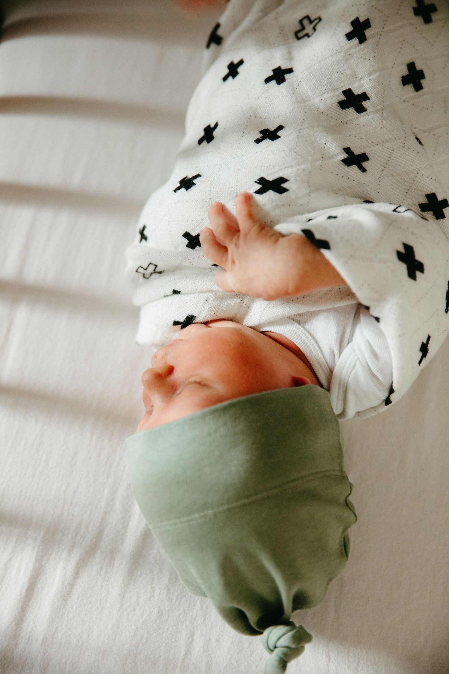 Close-up of newborn feet against white bedding with black cross pattern.