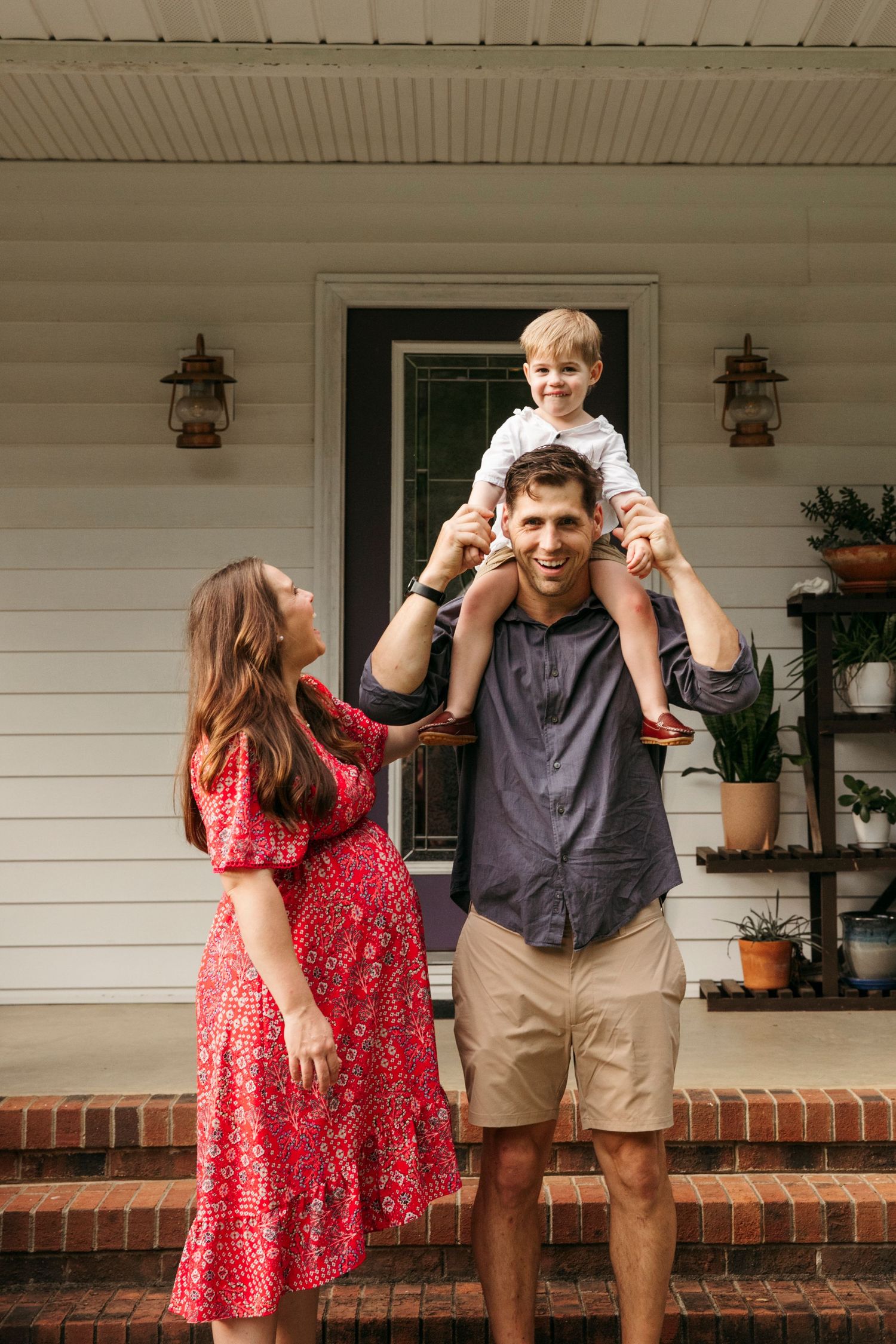 Family sharing playful moments together on white farmhouse porch with brick steps.