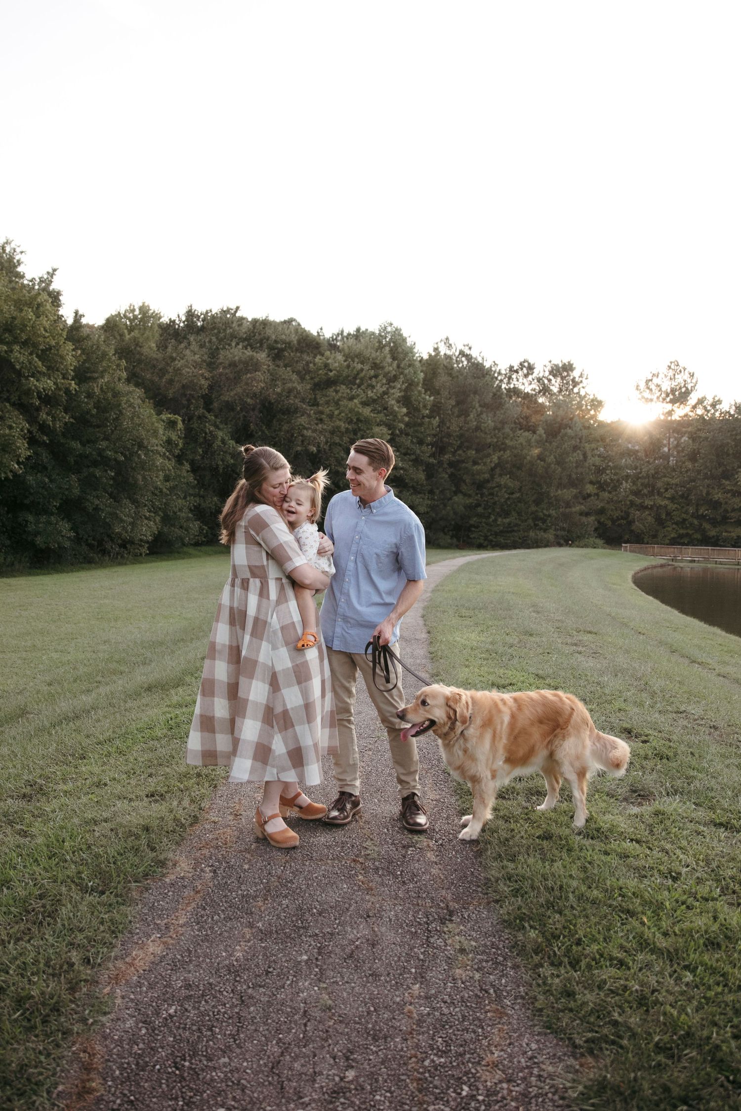 Family walking on path at sunset with their golden retriever dog.