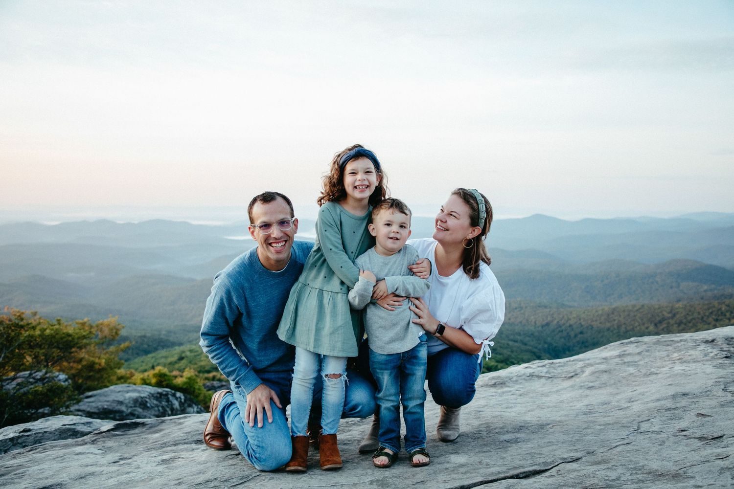 Family enjoying a scenic mountain view together while posing on a rocky overlook.