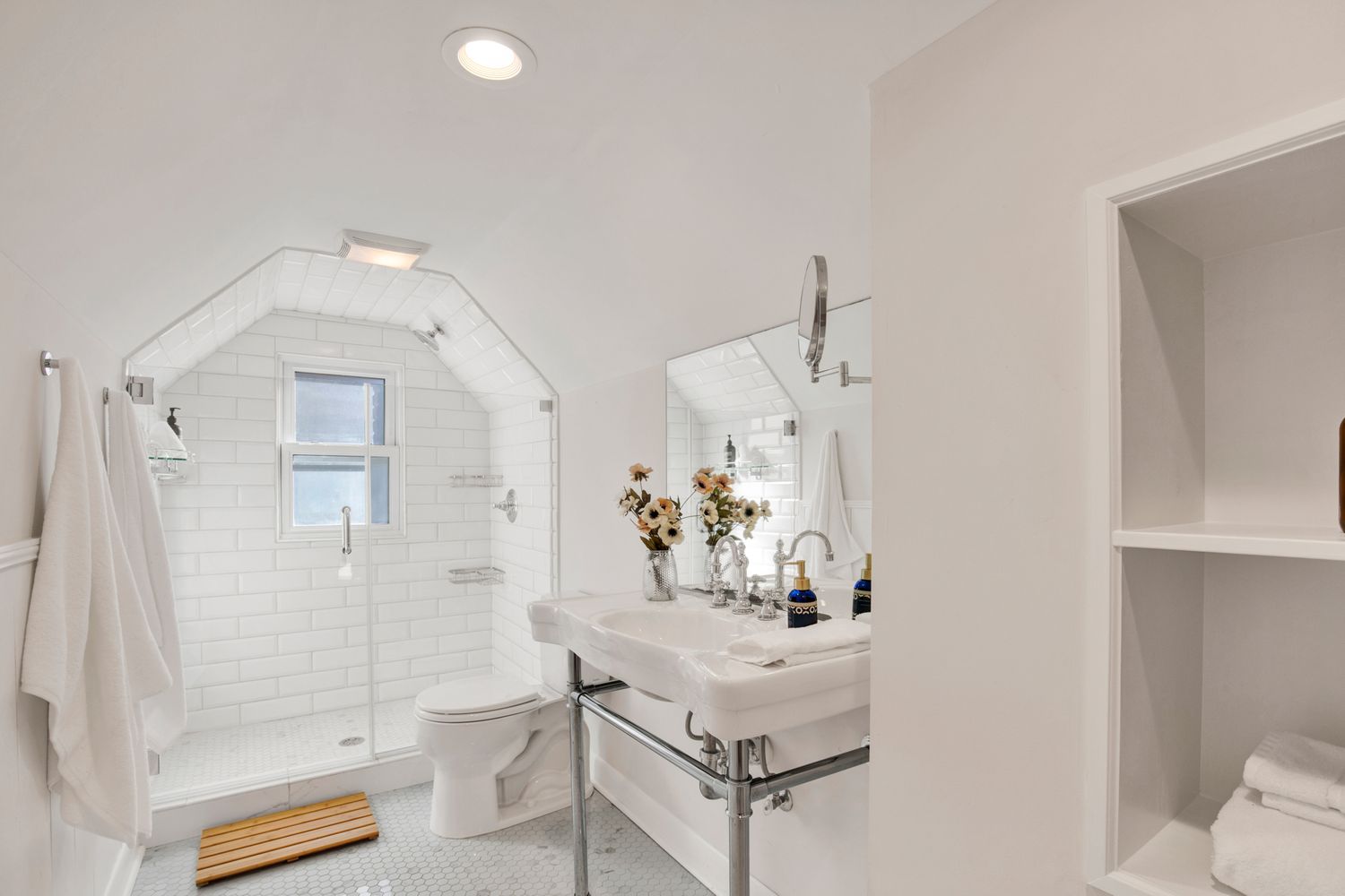White marble bathroom with glass shower enclosure and modern fixtures.