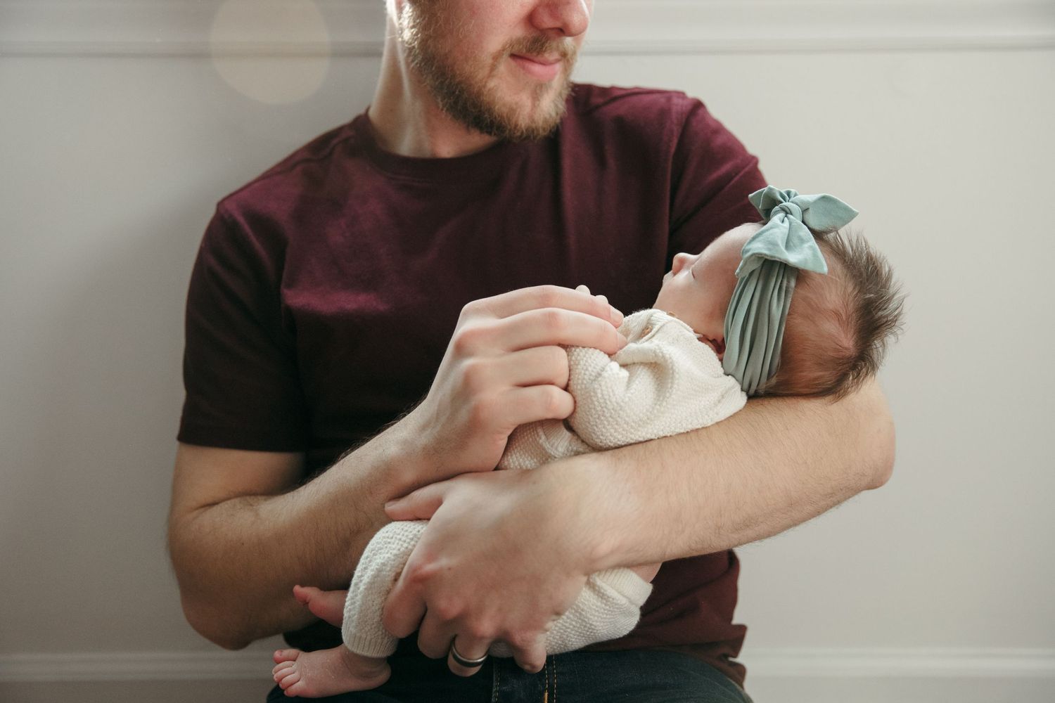Lifestyle photography showing tender moments of holding a newborn baby wrapped in white.