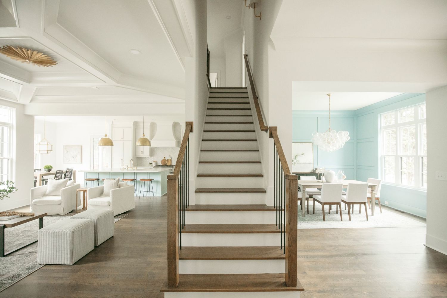 Open concept living space with central wooden staircase, white walls, and hardwood flooring.