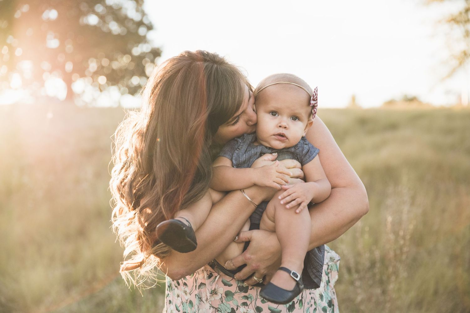 A tender moment captured in golden sunlight amidst tall grass.