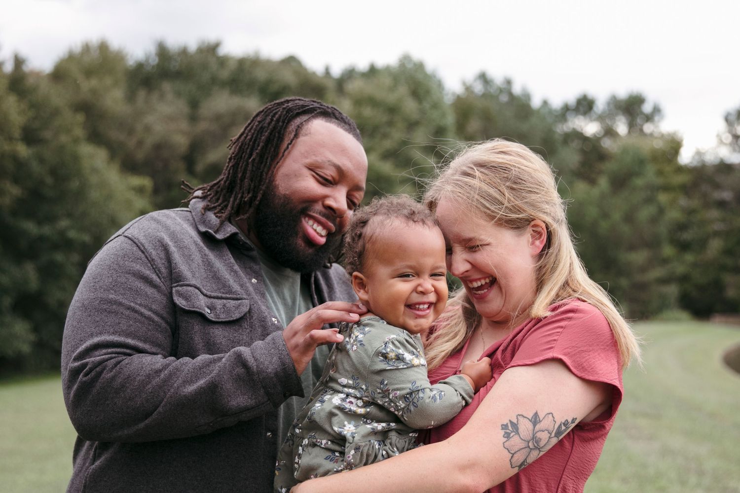 A happy family shares a loving moment of laughter together outdoors on a sunny day.