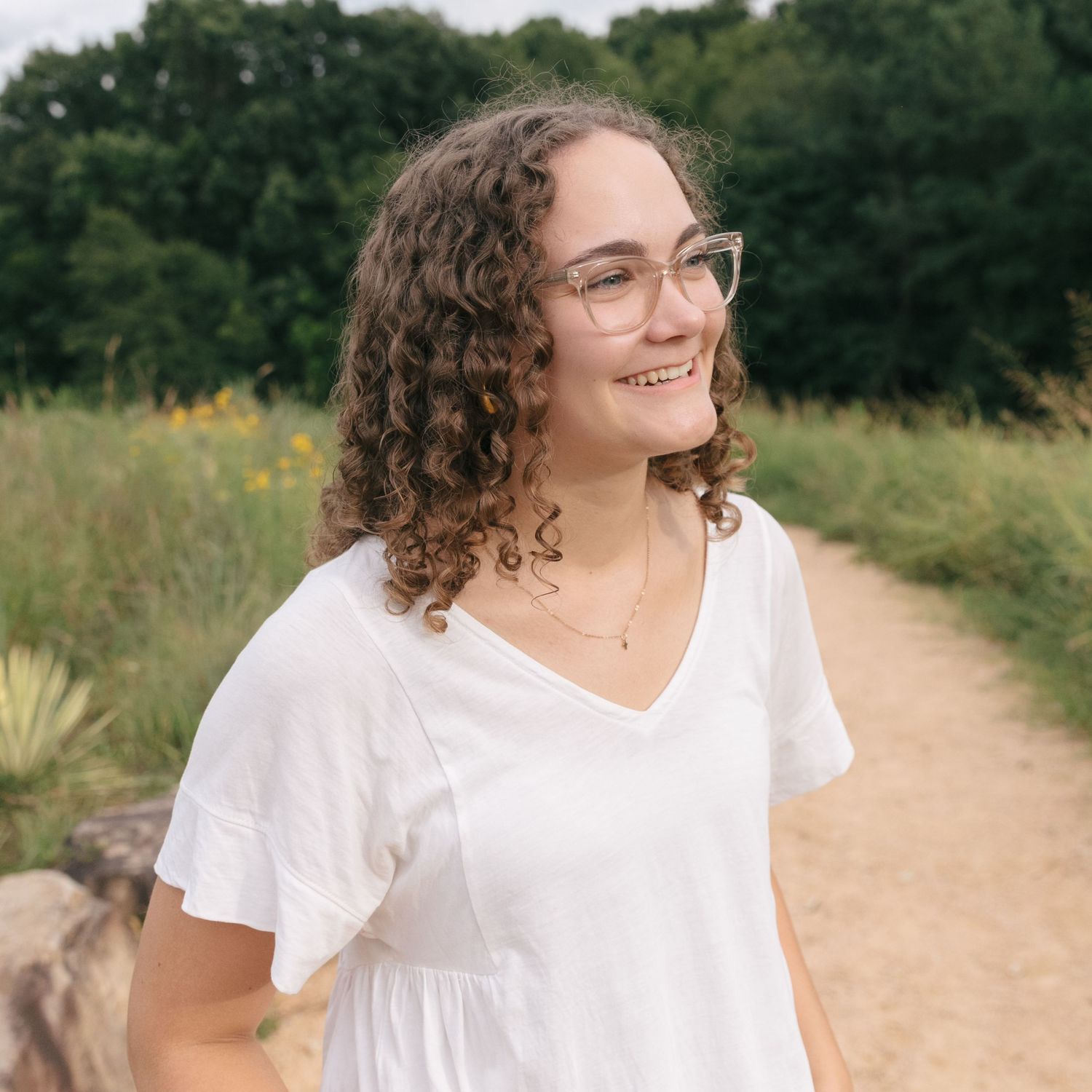 Summer portrait session on sandy path with wildflowers in background.