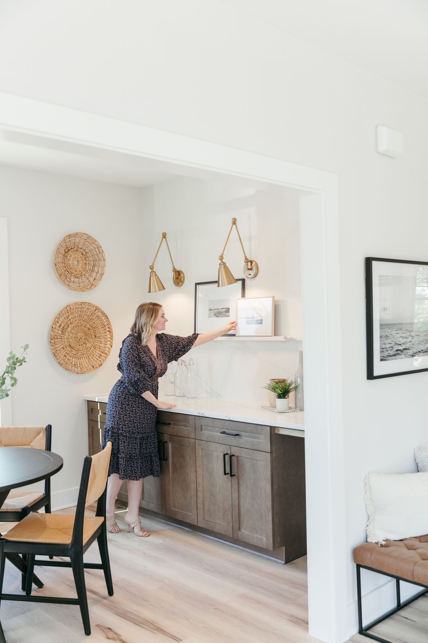 Minimalist dining area with woven wall decor and dark wood cabinets against white walls.