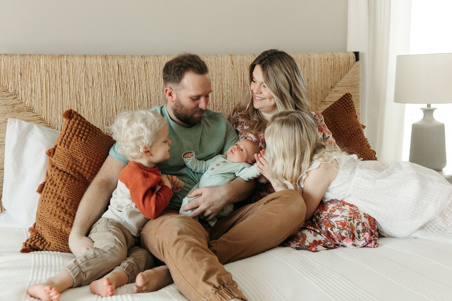 Family lounging together on a cozy bed in casual clothes sharing intimate moments.